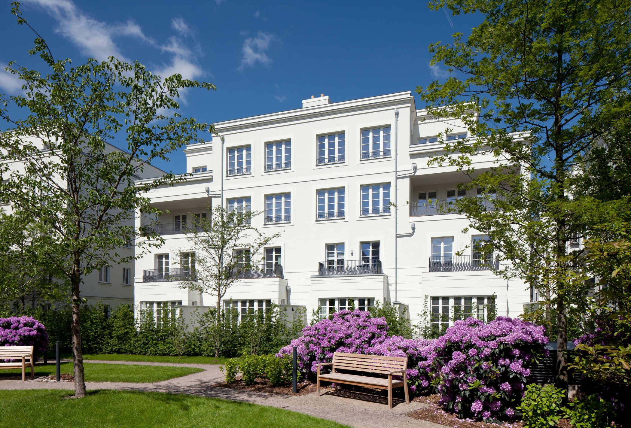 Blühende Parkanlage mit gepflegten Grünflächen vor der eleganten Architektur der Heinrich-Heine-Gärten in Düsseldorf