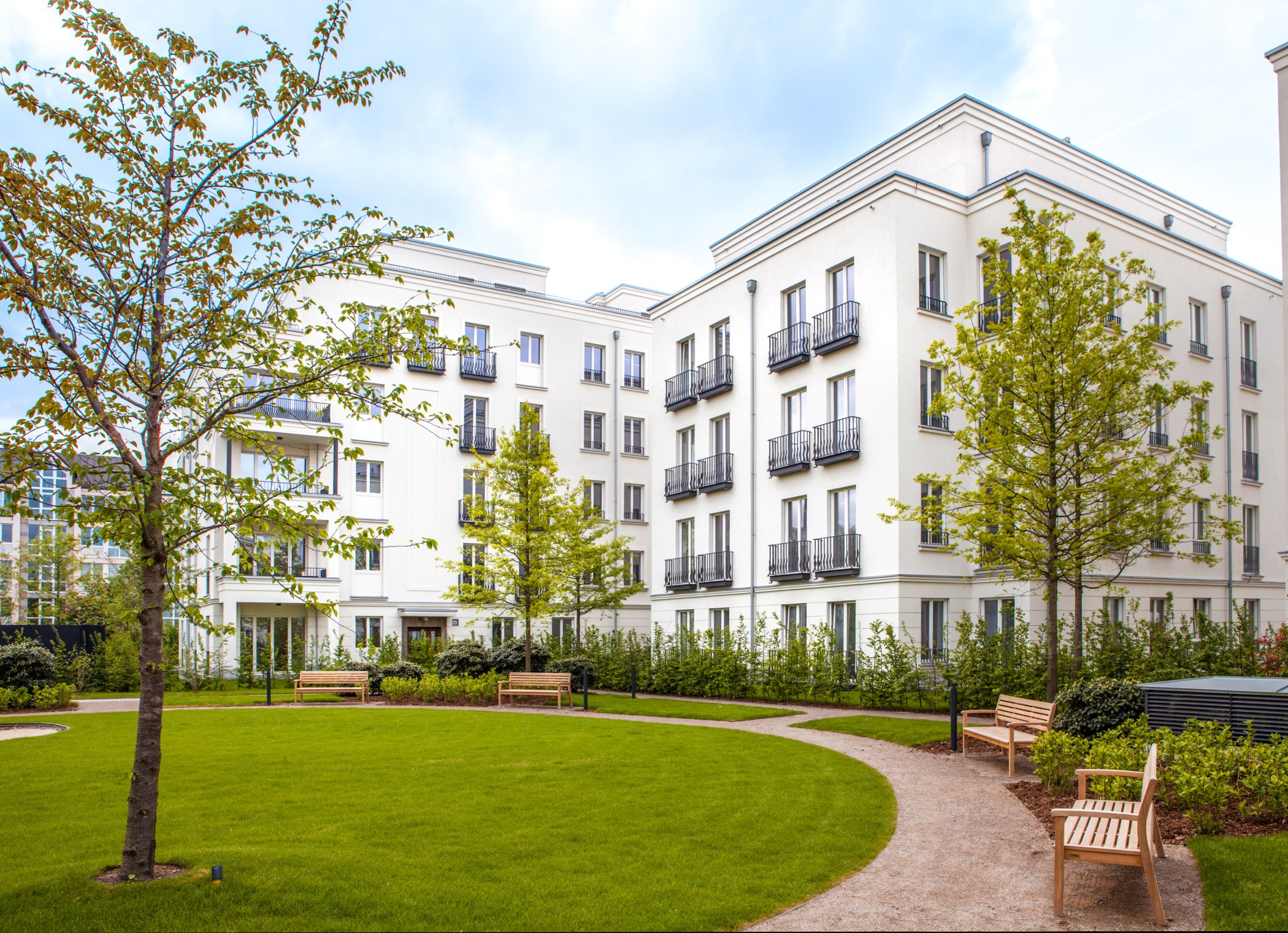 Parkanlage mit gepflegten Grünflächen vor der eleganten Architektur der Heinrich-Heine-Gärten in Düsseldorf