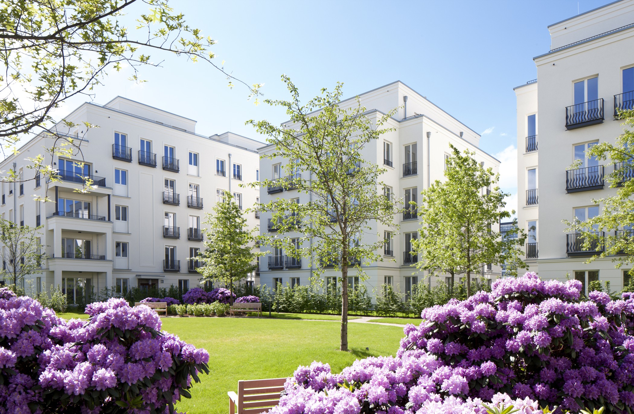 Blühende Parkanlage mit gepflegten Grünflächen vor der eleganten Architektur der Heinrich-Heine-Gärten in Düsseldorf