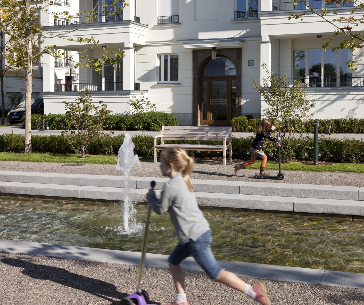 Wasseranlage mit Springbrunnen in der zentralen Parkanlage mit spielenden Kindern in den Heinrich-Heine-Gärten in Düsseldorf-Heerdt