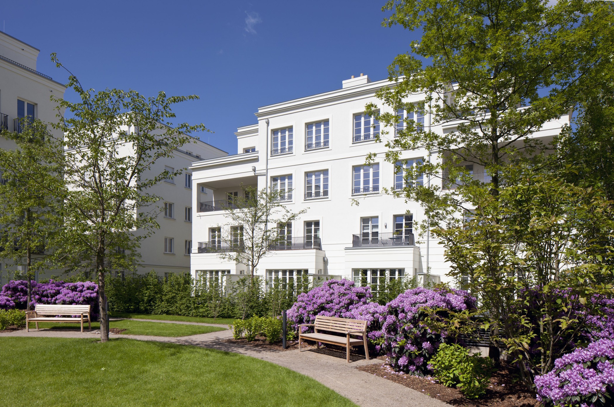 Blühende Parkanlage mit gepflegten Grünflächen vor der eleganten Architektur der Heinrich-Heine-Gärten in Düsseldorf